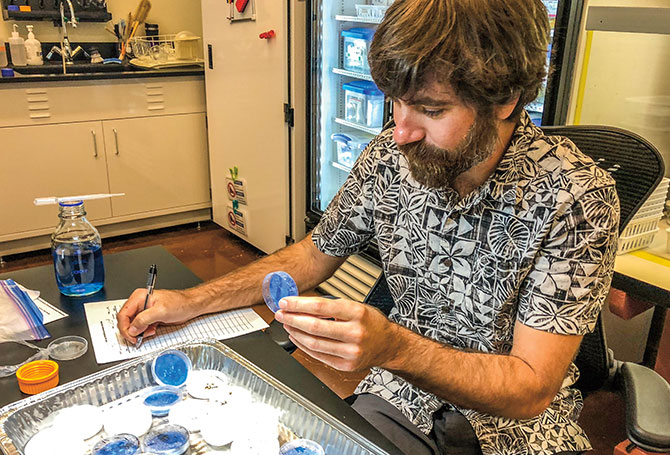 Wolkis holds a sample as he makes notes.