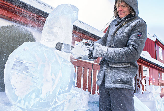 A man carves an instrument out of ice with a chainsaw.