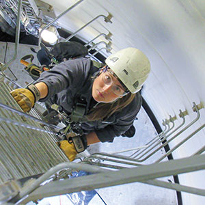 A picture taken directly above a person climbing a tall ladder and looking up determinedly