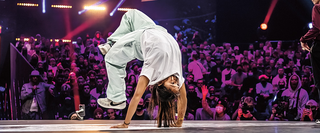 Image of a person break dancing on a stage in front of an audience