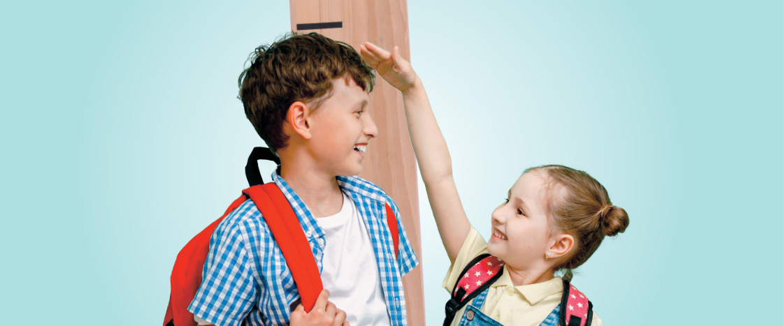 Image of a brother measuring his height and sister holding her hand up to his head