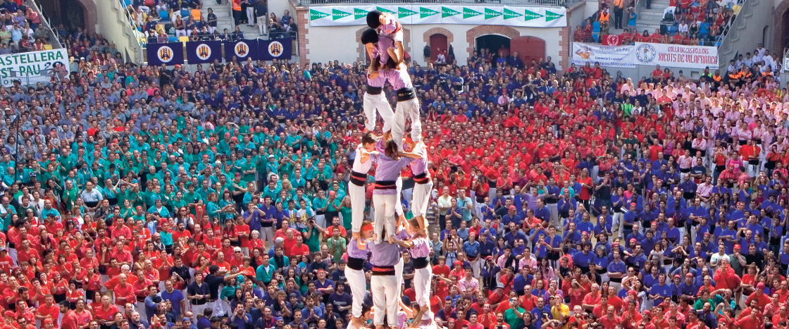 Photo of a huge crowd gathered in matching shirts to watch a human tower