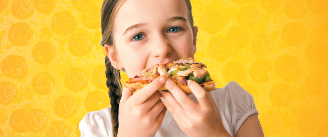 Image of kid eating slice of pizza with a bunch of toppings